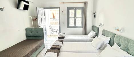 A hotel room with two beds, a television, a window, and a door leading to a balcony.