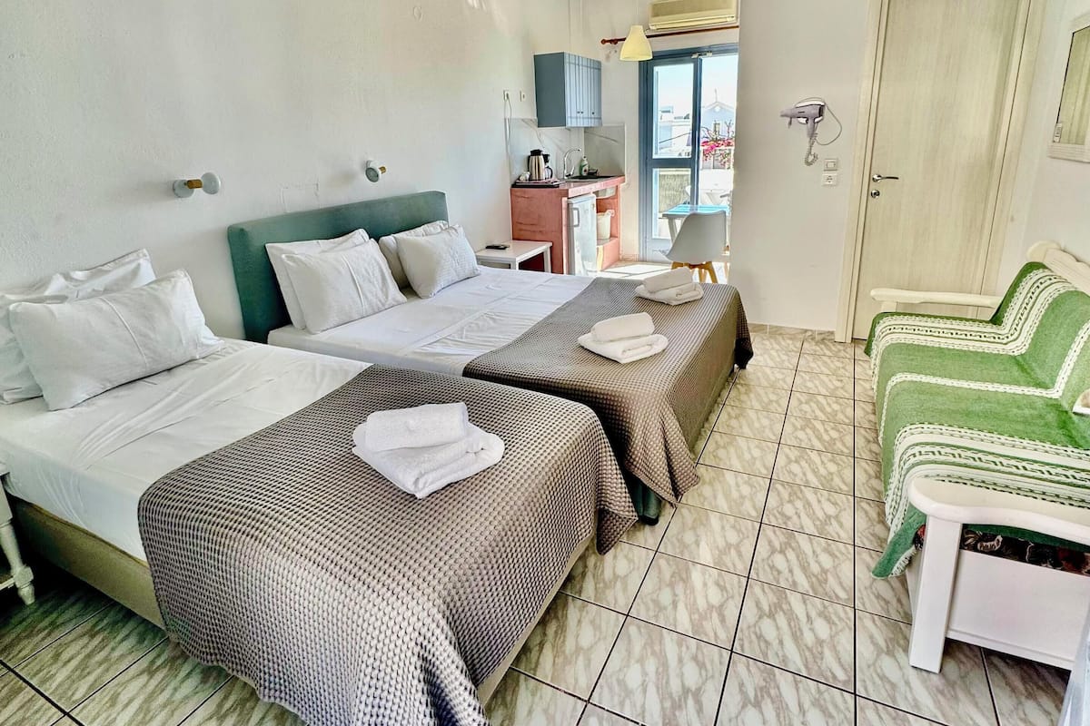 A hotel room with two beds, a desk, a chair, and a view of the outside.