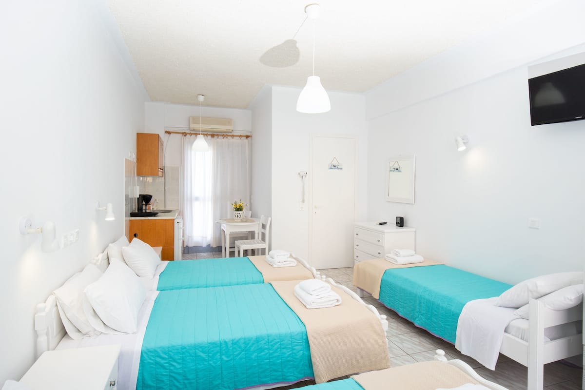 A hotel room with two beds, a desk, a chair, a TV, and a window with curtains.