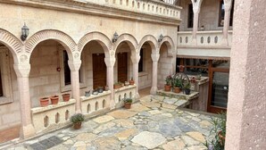 A courtyard with stone flooring, arched alcoves, and potted plants. - Nature Park Cave Hotel (Nevsehir)