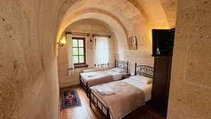 A room with two beds, a window with curtains, a radiator, and a wooden floor. - Nature Park Cave Hotel (Nevsehir)