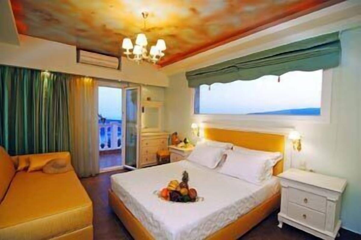 Una habitación de hotel con cama, sofá, mesita de noche y ventana con vistas.