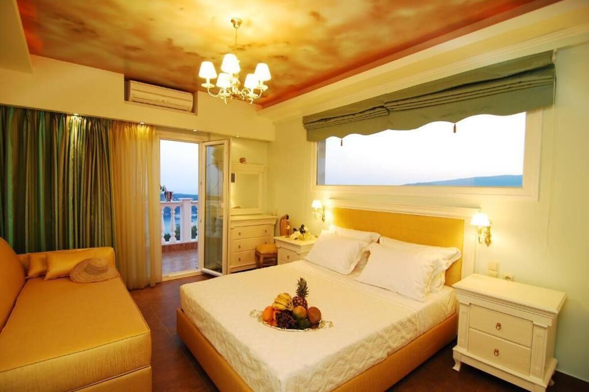 Habitació d'hotel amb llit, sofà, tauleta de nit, finestra amb vistes i un penjoll.