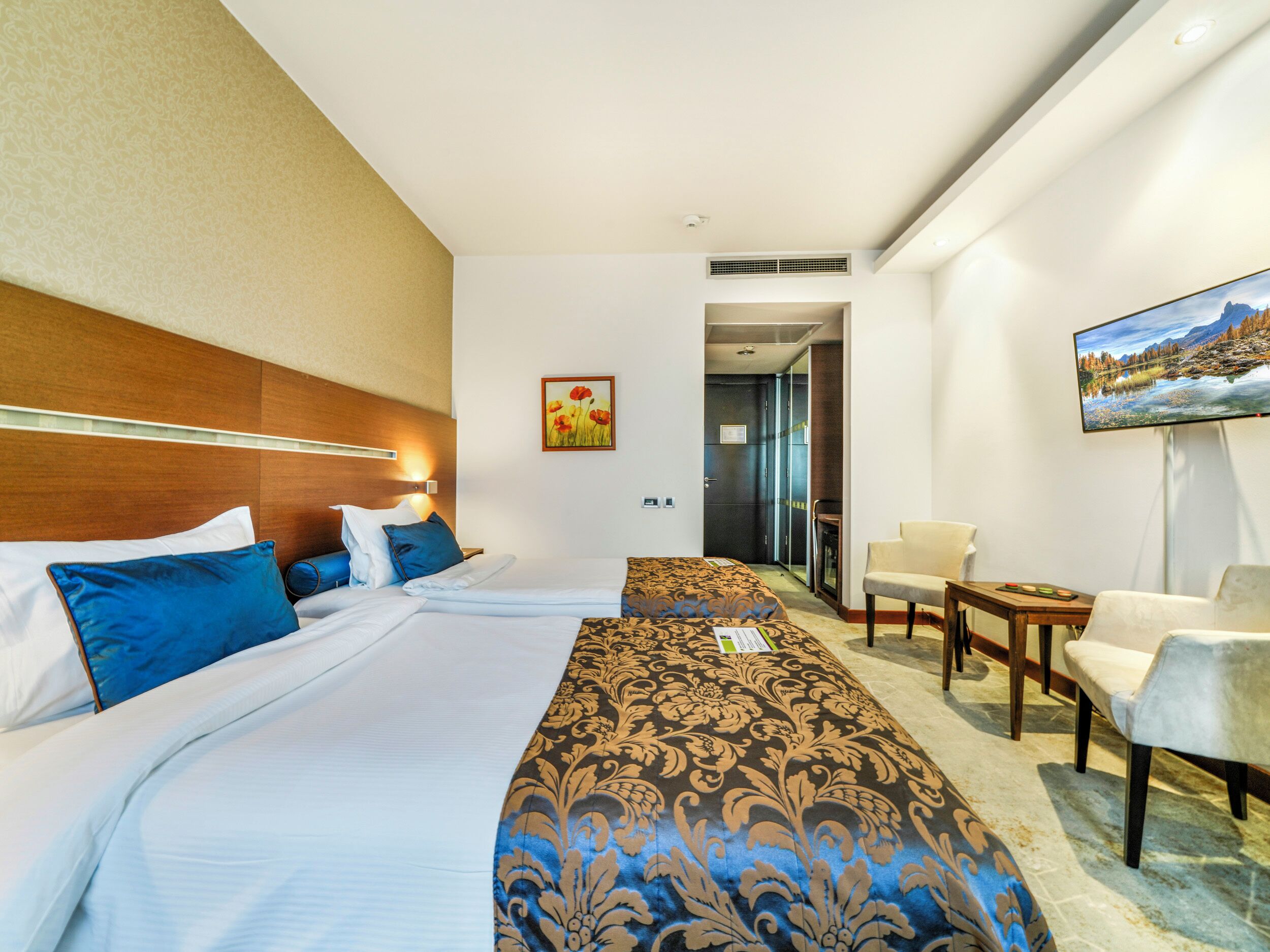 Una habitación de hotel con una cama grande, un escritorio, una silla y un televisor en la pared.