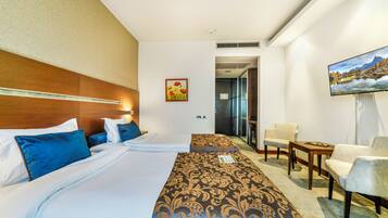 Una habitación de hotel con una cama grande, un escritorio, una silla y un televisor en la pared.