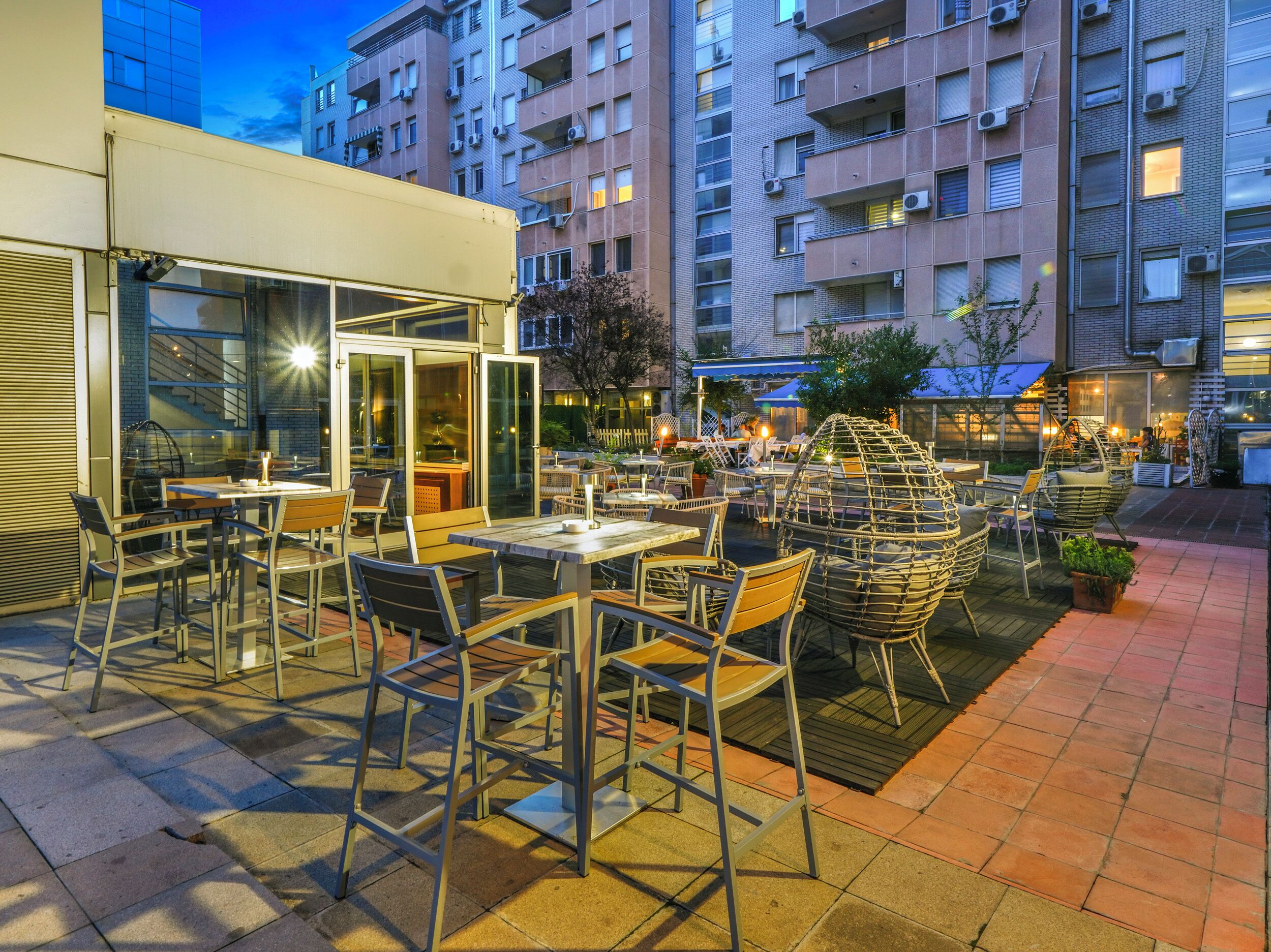 Een terras met tafels en stoelen, omringd door gebouwen.