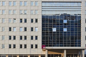 A modern hotel building with a reflective glass facade and a sign reading "IN HOTEL".