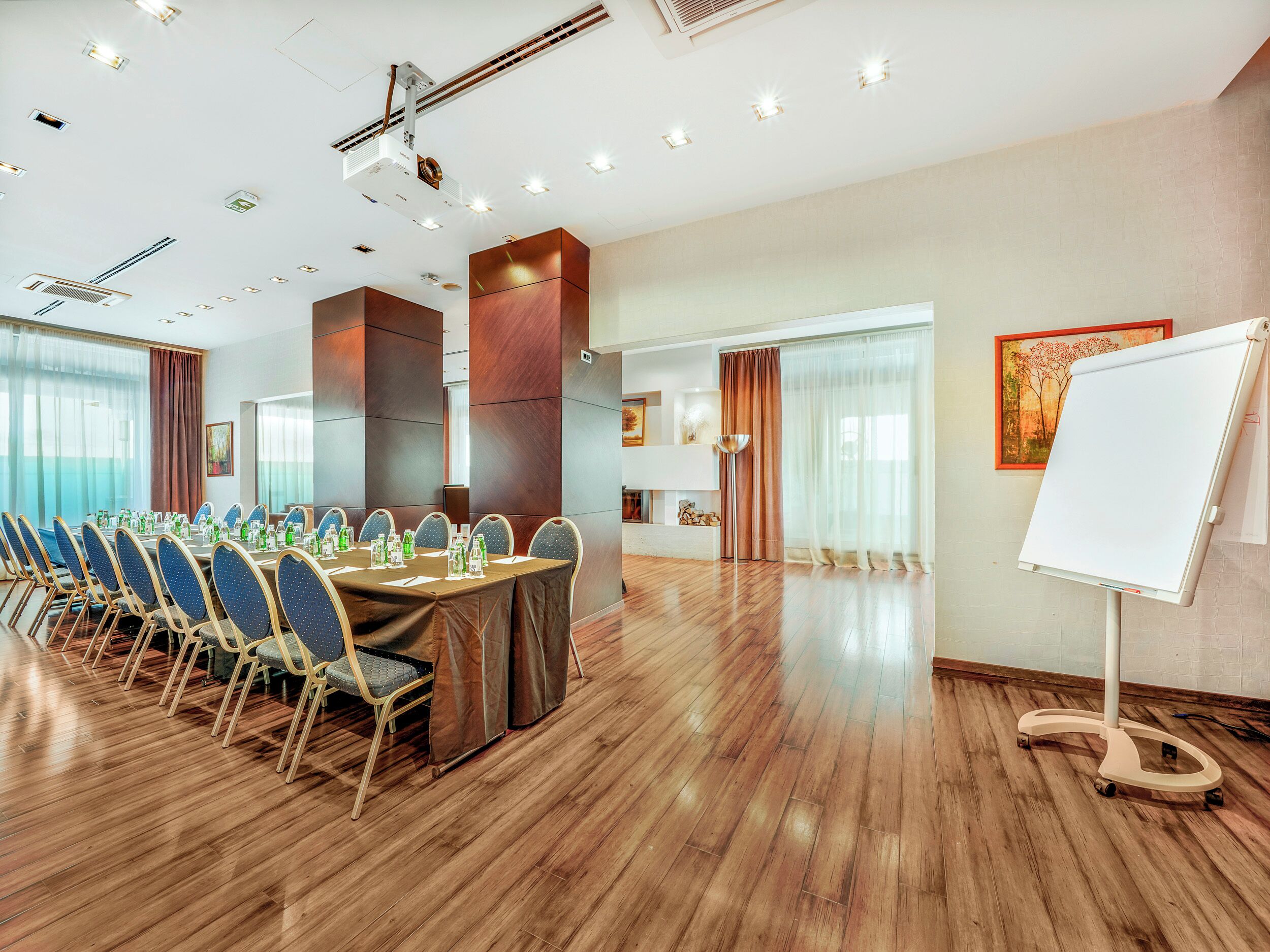 Un salón de conferencias con una larga mesa, sillas, una pizarra y un proyector.