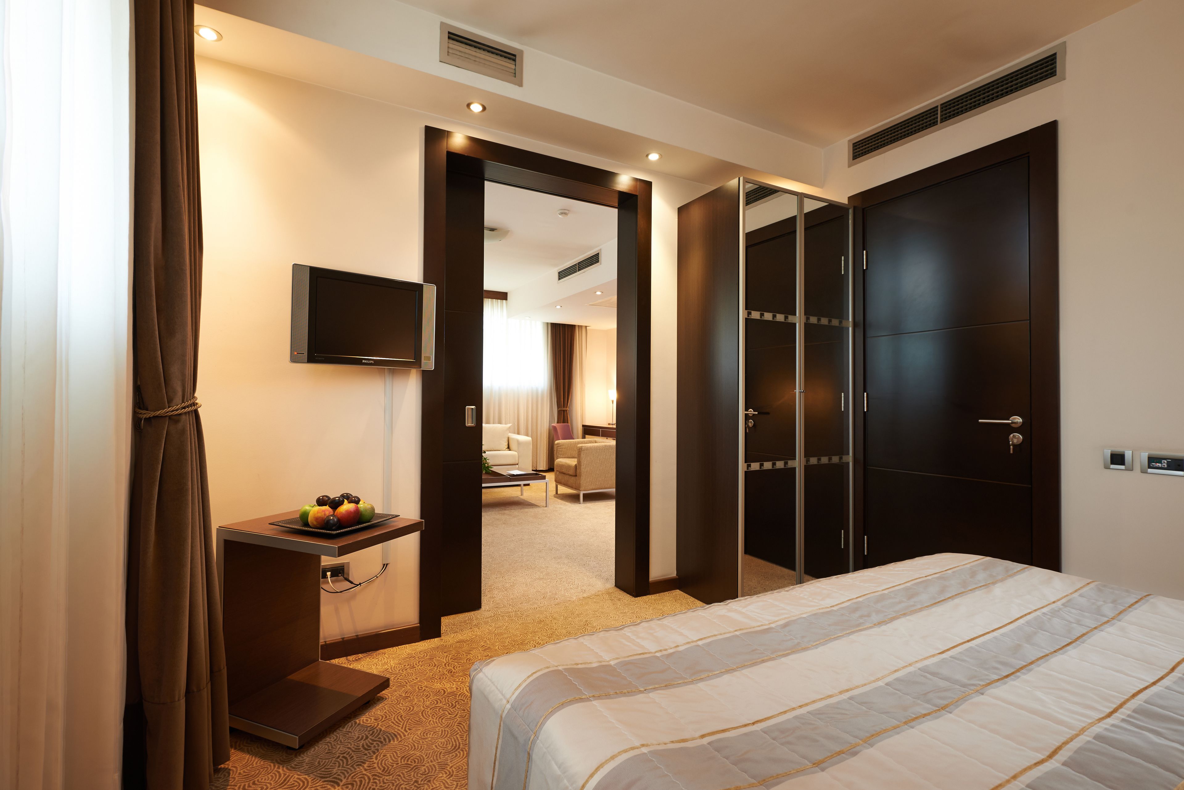 Una habitación de hotel con una cama, un escritorio con fruta, un televisor y un armario.