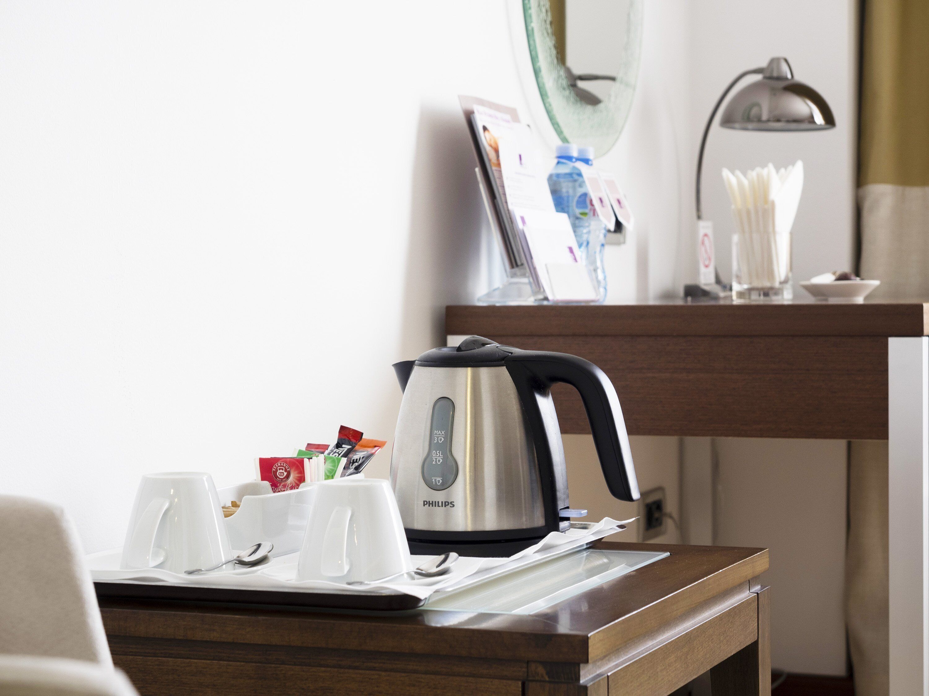 A hotel room with a coffee maker, cups, and a tray.