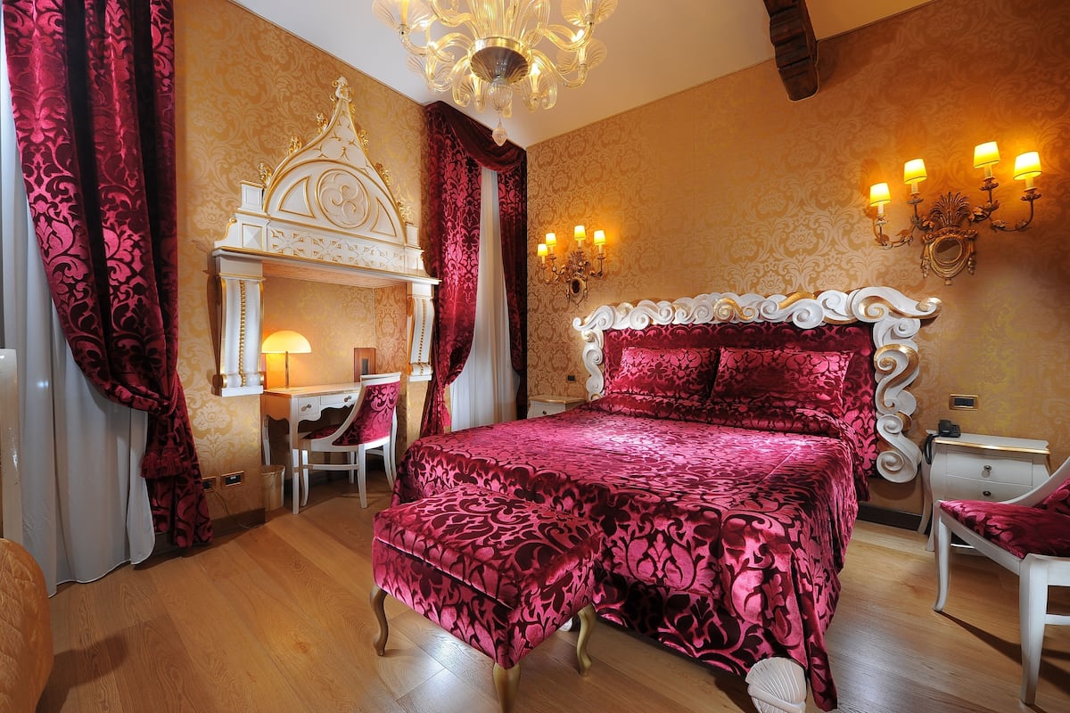 Une chambre à coucher avec un grand lit, une coiffeuse avec un miroir et un lustre.