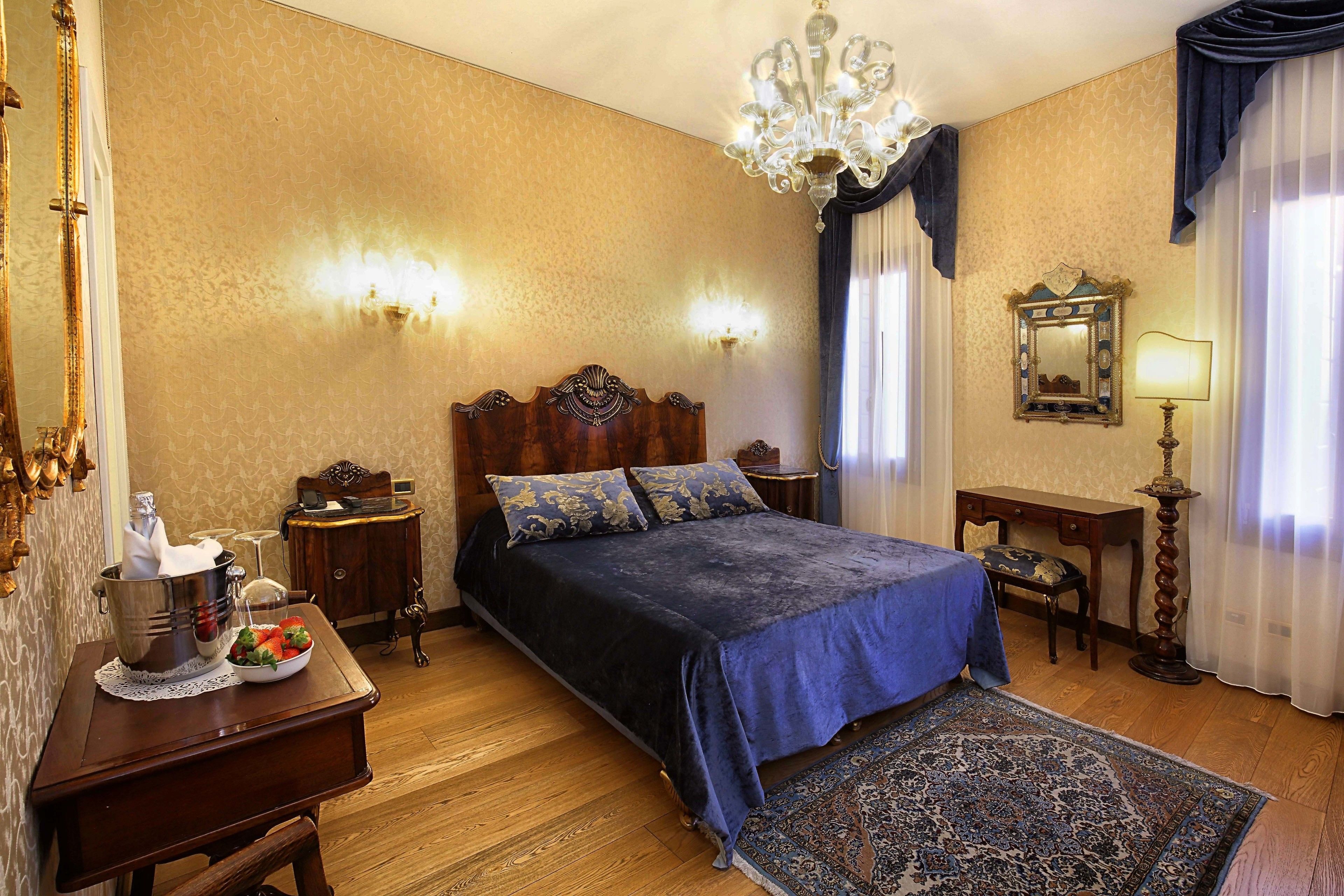 A bedroom with a large bed, a wooden nightstand, a dresser, a chandelier, and a mirror.