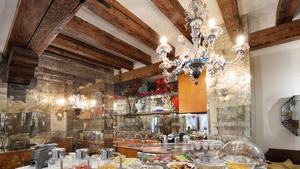 Un buffet de petit-déjeuner proposant une variété d’aliments et de boissons, un lustre et des poutres en bois au plafond.