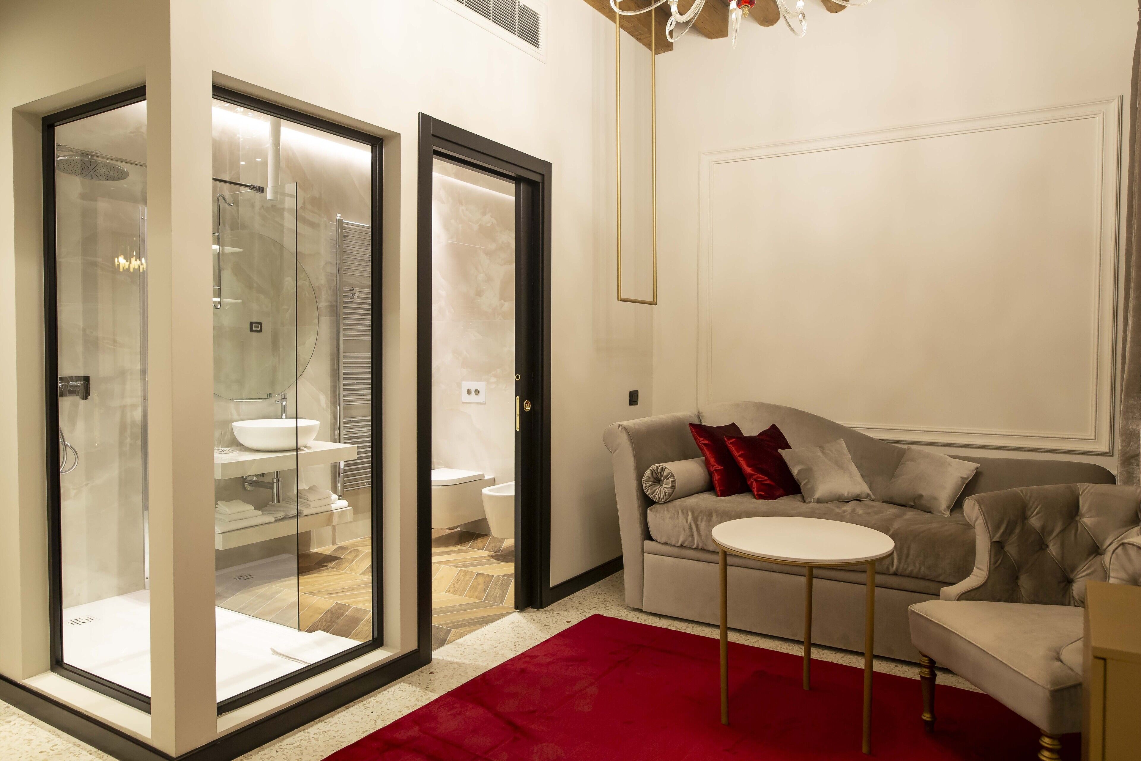 Una sala moderna con un sofá gris, una mesita redonda y un tapete rojo.