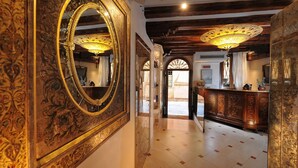 Un couloir agrémenté de miroirs décoratifs, de poutres en bois au plafond et d’un sol en marbre.