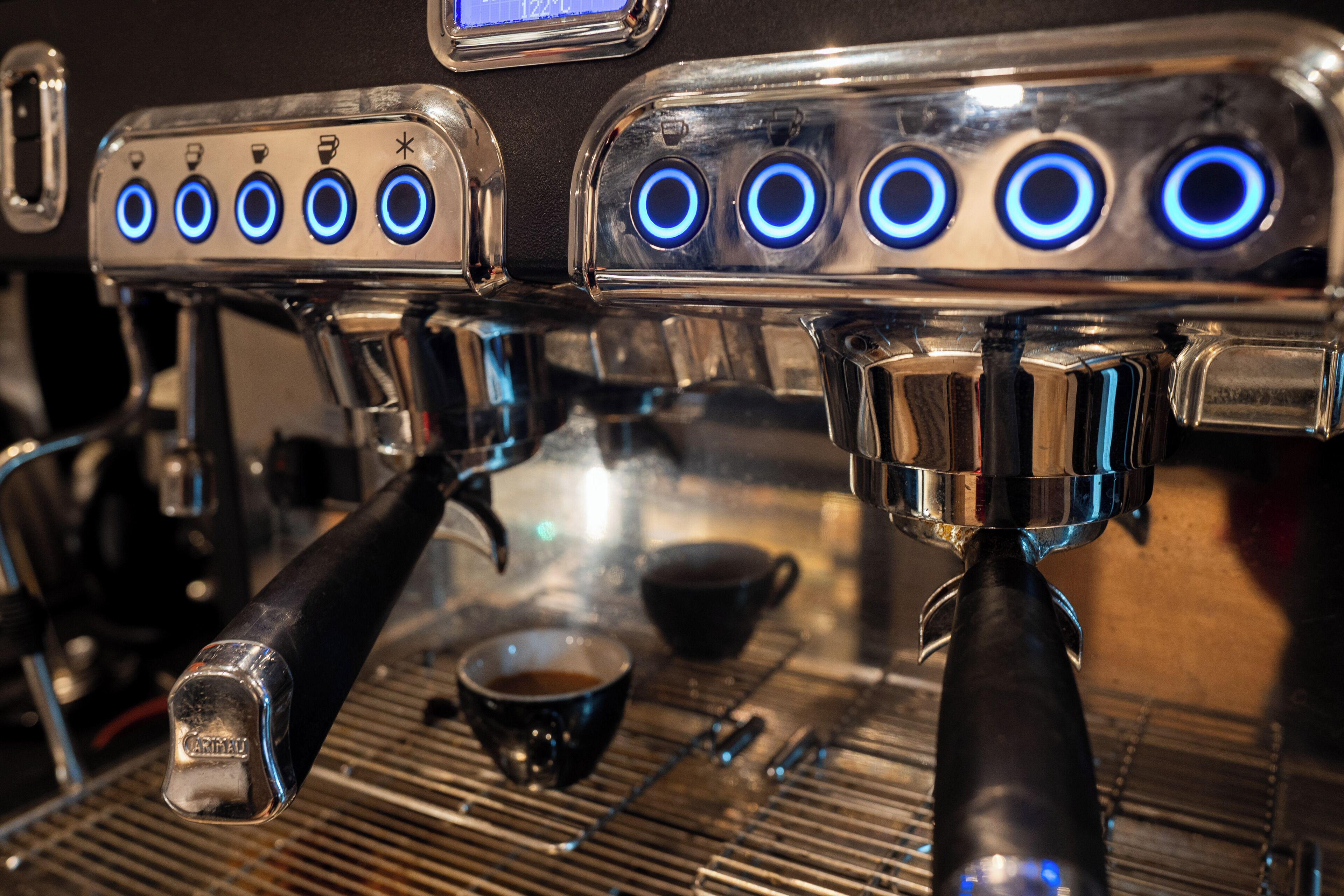 Een koffieapparaat met meerdere stoomuitgangen en een digitaal scherm.