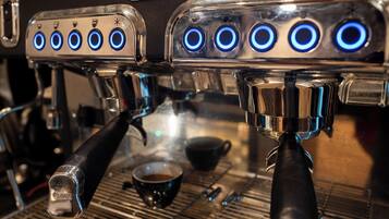 Een koffieapparaat met meerdere stoomuitgangen en een digitaal scherm.