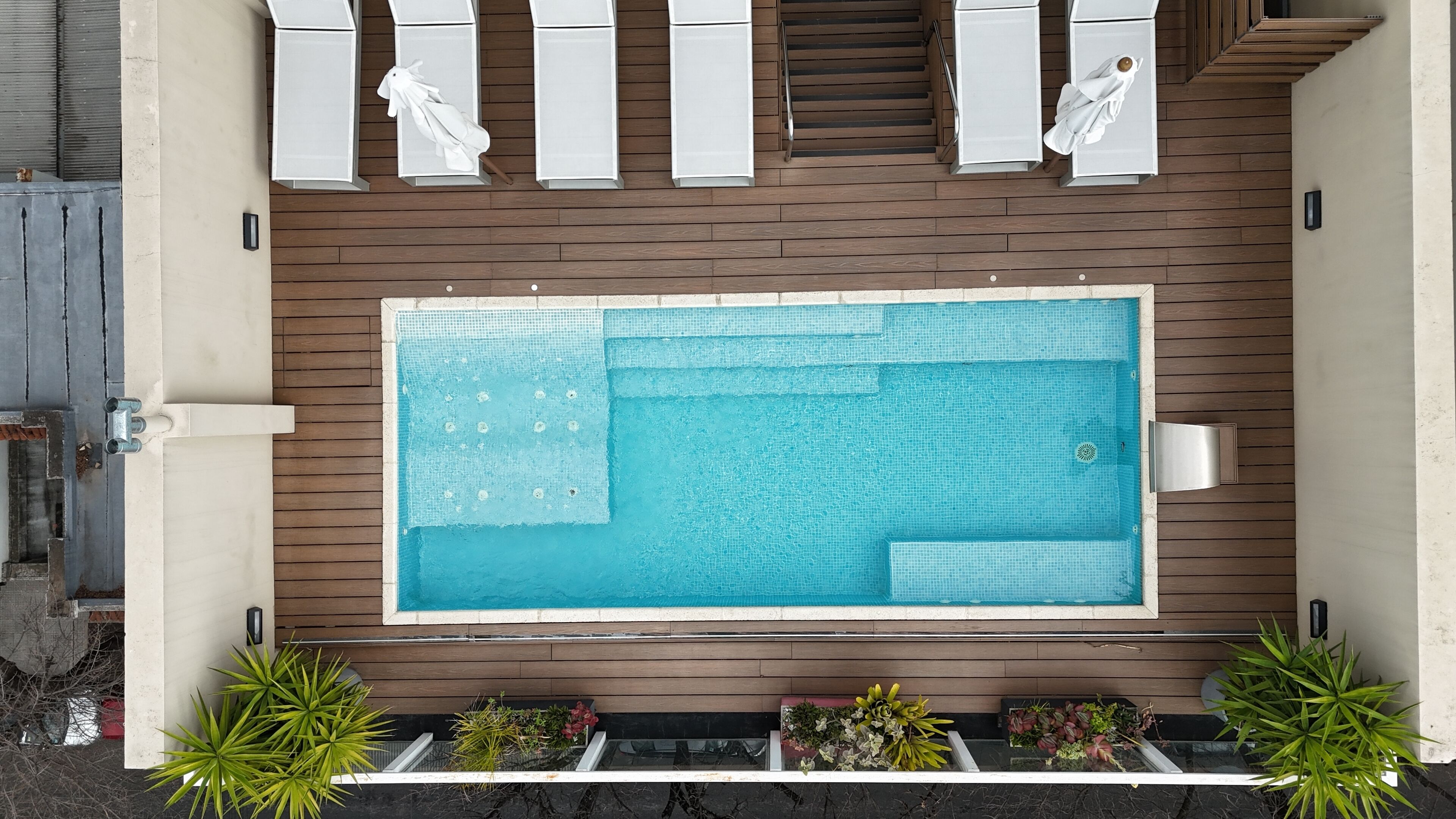 Una piscina rectangular con muelle de madera que la rodea, equipada con un sistema de filtrado de agua.
