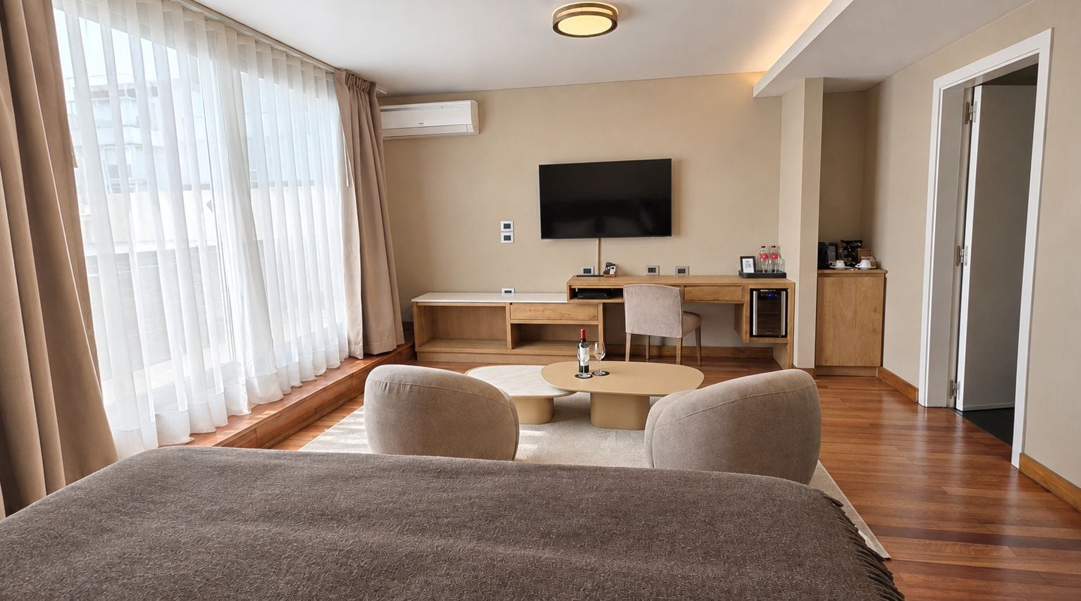 A hotel room with a bed, a desk, a chair, a TV, and a coffee machine.