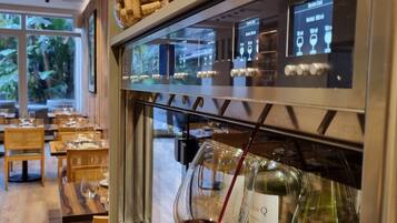 Una copa de vino siendo servida en un bar con una pantalla digital de menú.