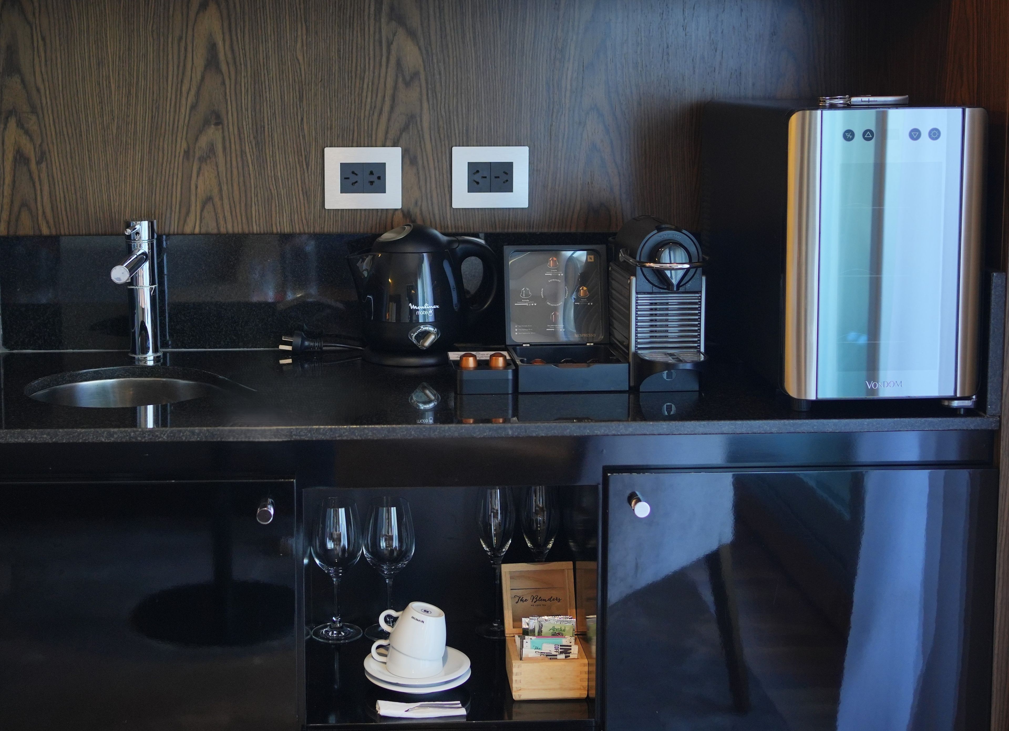 A modern kitchen with a stainless steel refrigerator, a coffee maker, and a kettle.
