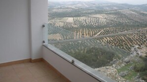 Ein Balkon mit freiem Blick auf terrassenförmig angelegte Felder und ferne Berge.