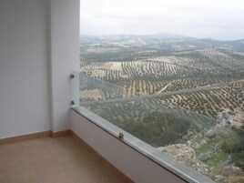 Un balcón con vistas despejadas a campos escalonados y montañas lejanas.