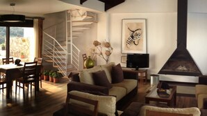 Ein stilvolles Wohnzimmer mit einer Couch, Sesseln, einem Esstisch und einem Kamin.