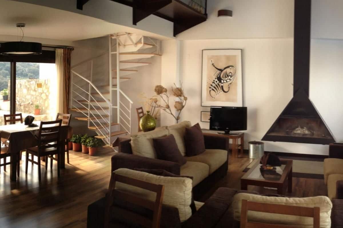 A modern living room with a sofa, chairs, a dining table, and a fireplace.