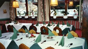 A dining area with tables set for multiple guests, chairs with unique circular backrests, and potted plants on windowsills. - Gasthof Goldener Stern (Sankt Koloman)