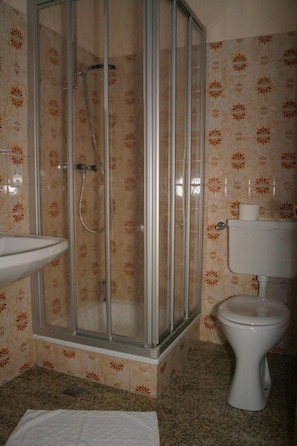 Casa de banho com chuveiro, pia e sanita.