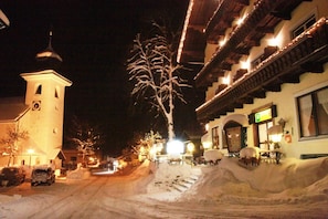 Uma rua coberta de neve, com uma igreja e um edifício com varanda.