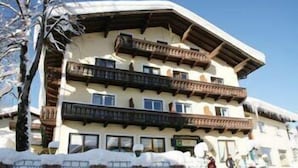A multi-story building with balconies, snow on the ground, and a clear sky. - Gasthof Goldener Stern (Sankt Koloman)