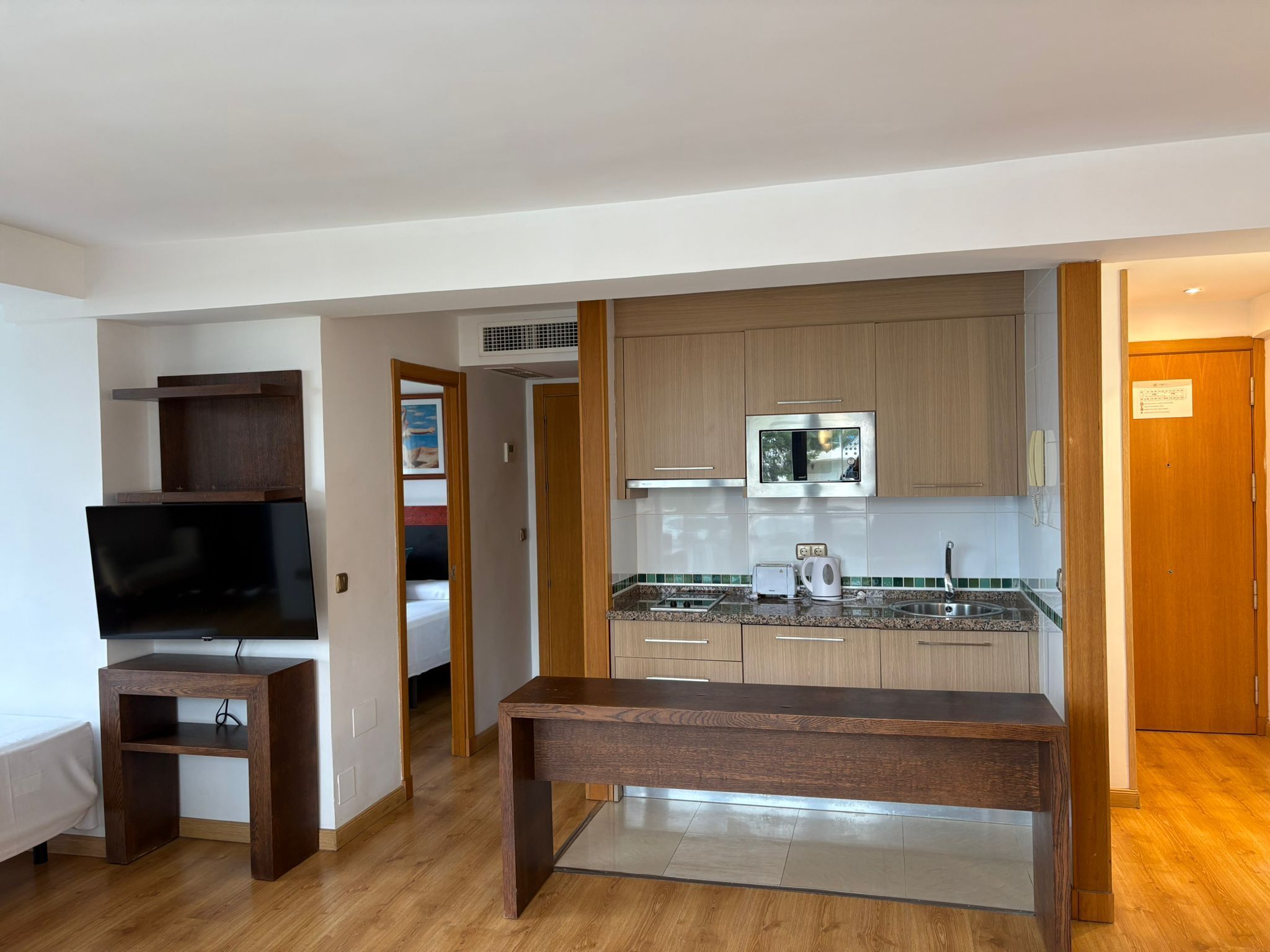 A modern kitchen with wooden cabinets, a built-in microwave, and a stainless steel sink.