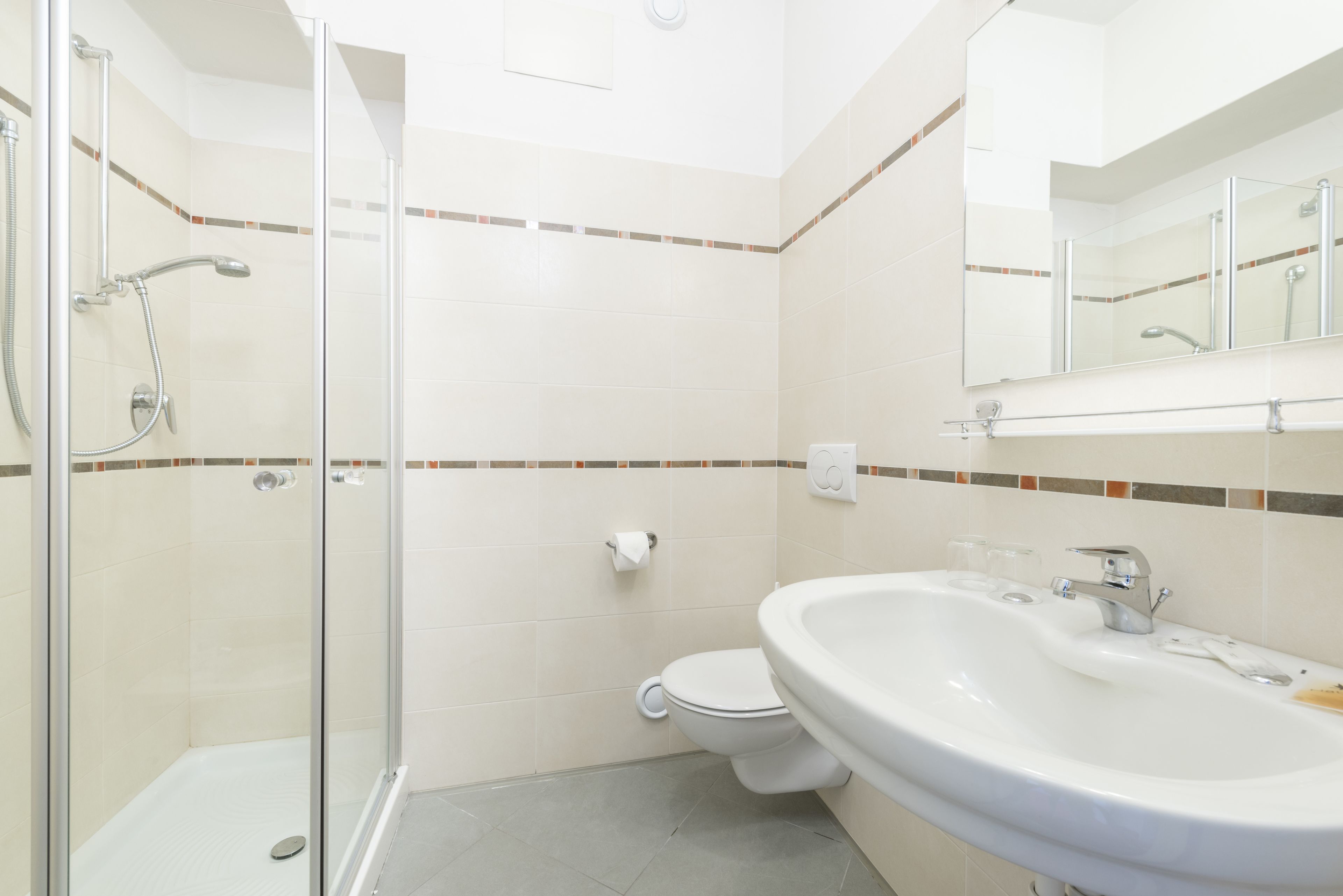 A bathroom with a glass shower enclosure, a toilet, and a sink with a mirror above it.