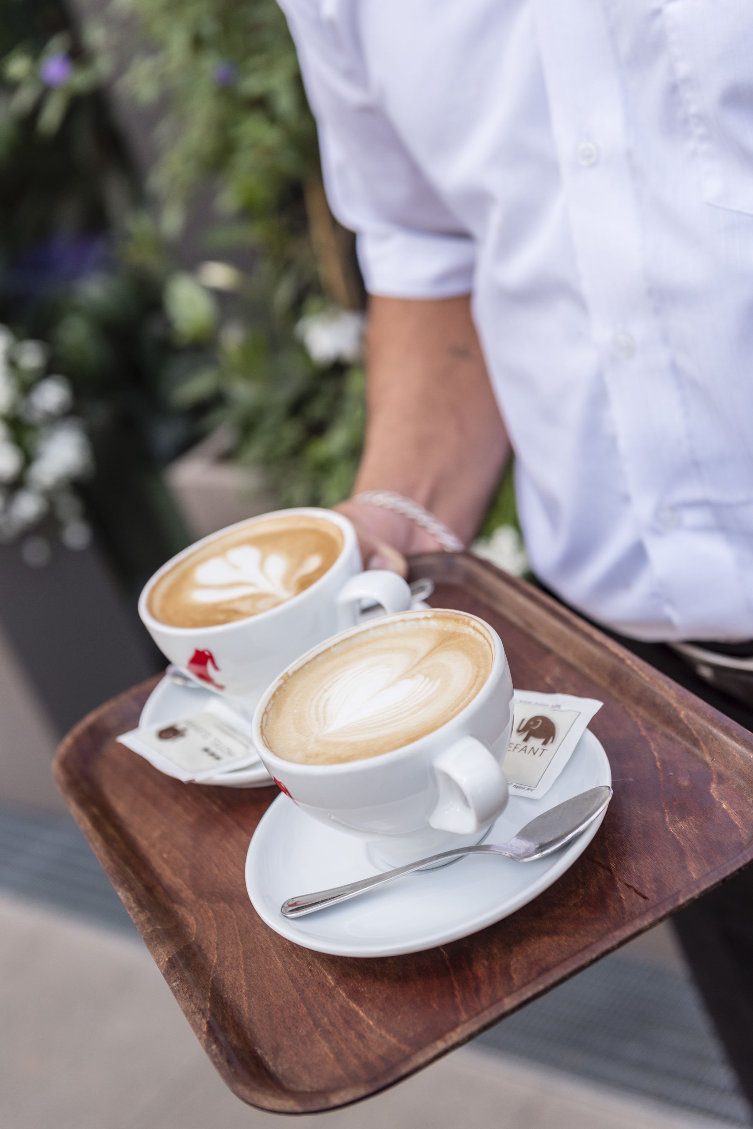 A tray with two cups of coffee and a spoon.