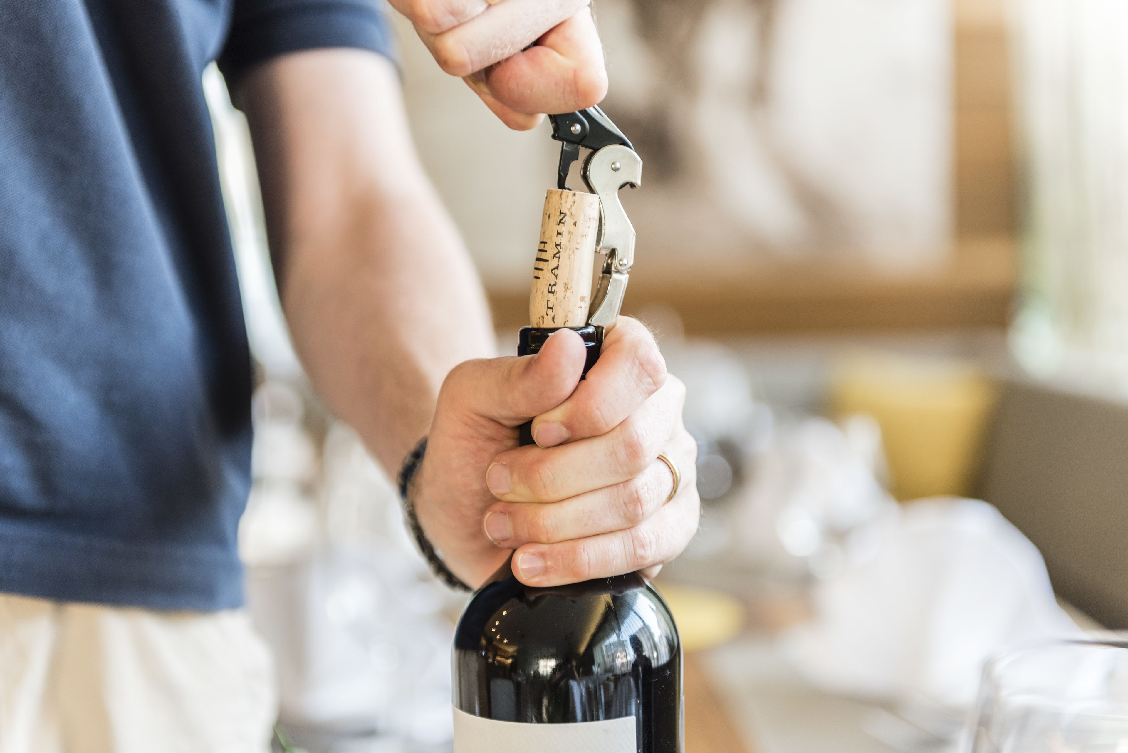 Une personne qui ouvre une bouteille de vin à l’aide d’un tire-bouchon.