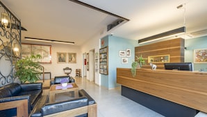 A modern reception area with a wooden reception desk, leather seating, and framed pictures on the walls. - Elefant (Ora)