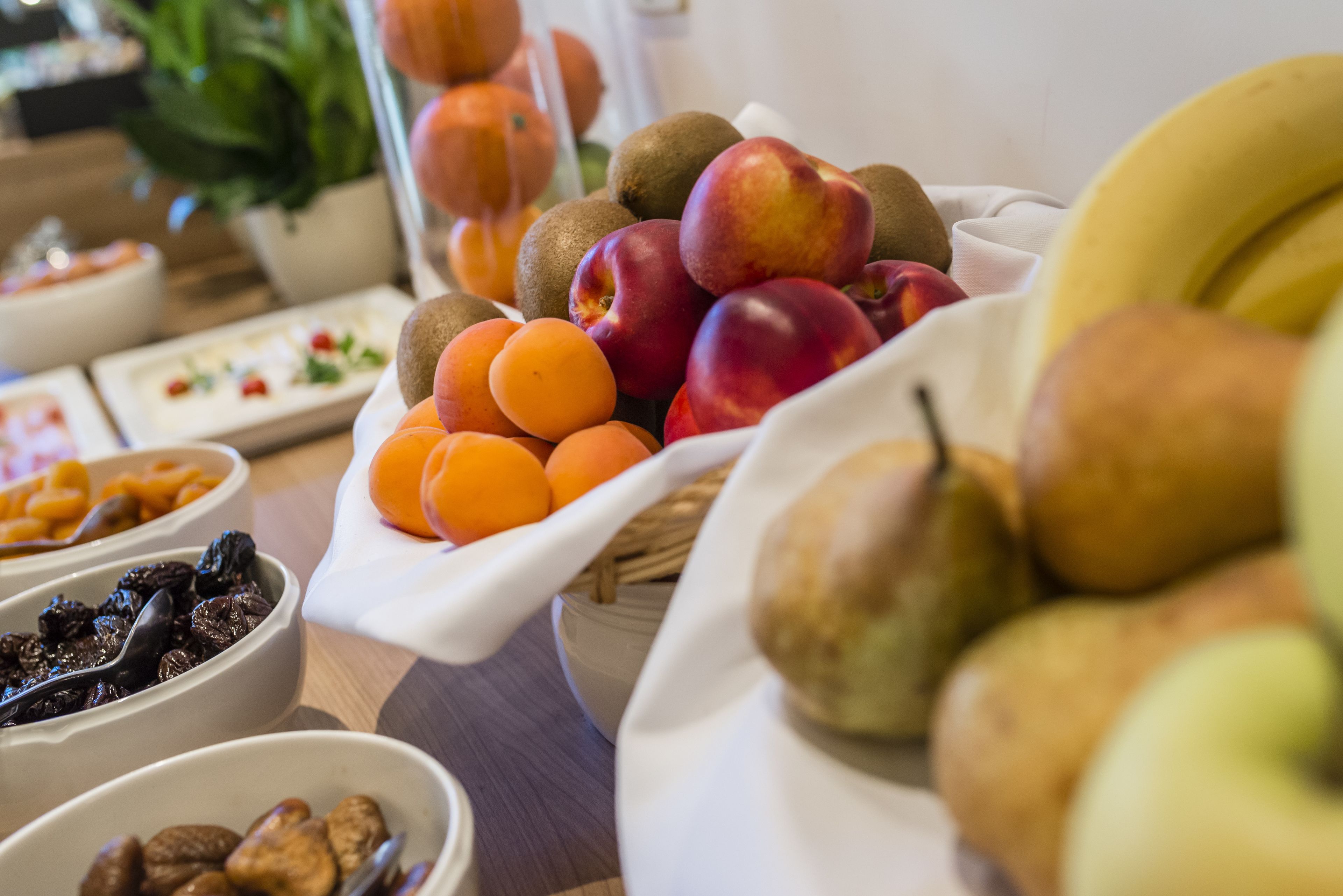 A variety of fruits and nuts arranged on a table, including kiwis, peaches, apricots, and walnuts.