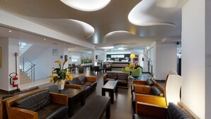 A modern hotel lobby with leather seating, a bar area, and a staircase. - Hotel Monte Sarago (Ostuni)