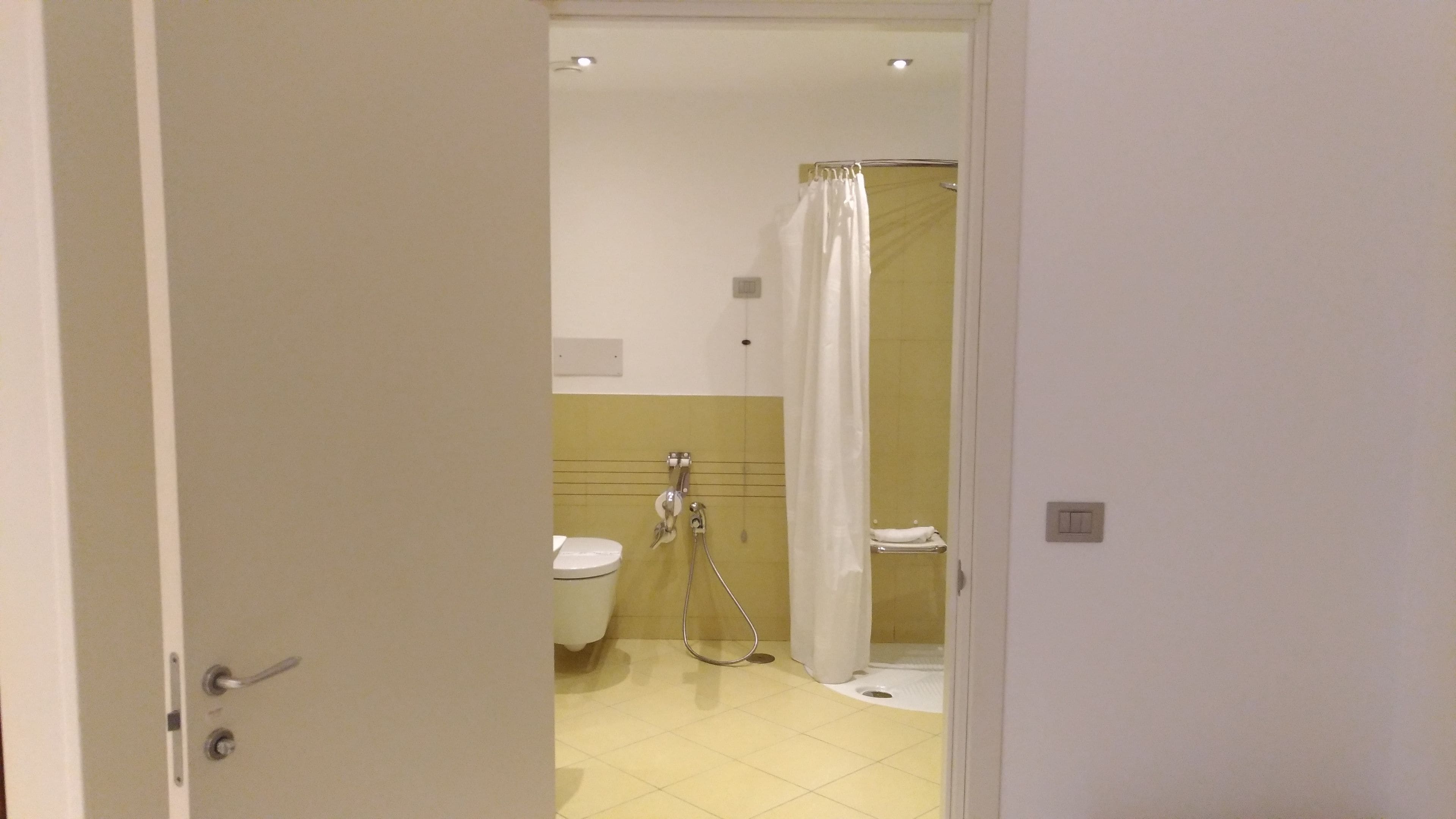 A bathroom with a toilet, a shower with a curtain, and a sink.