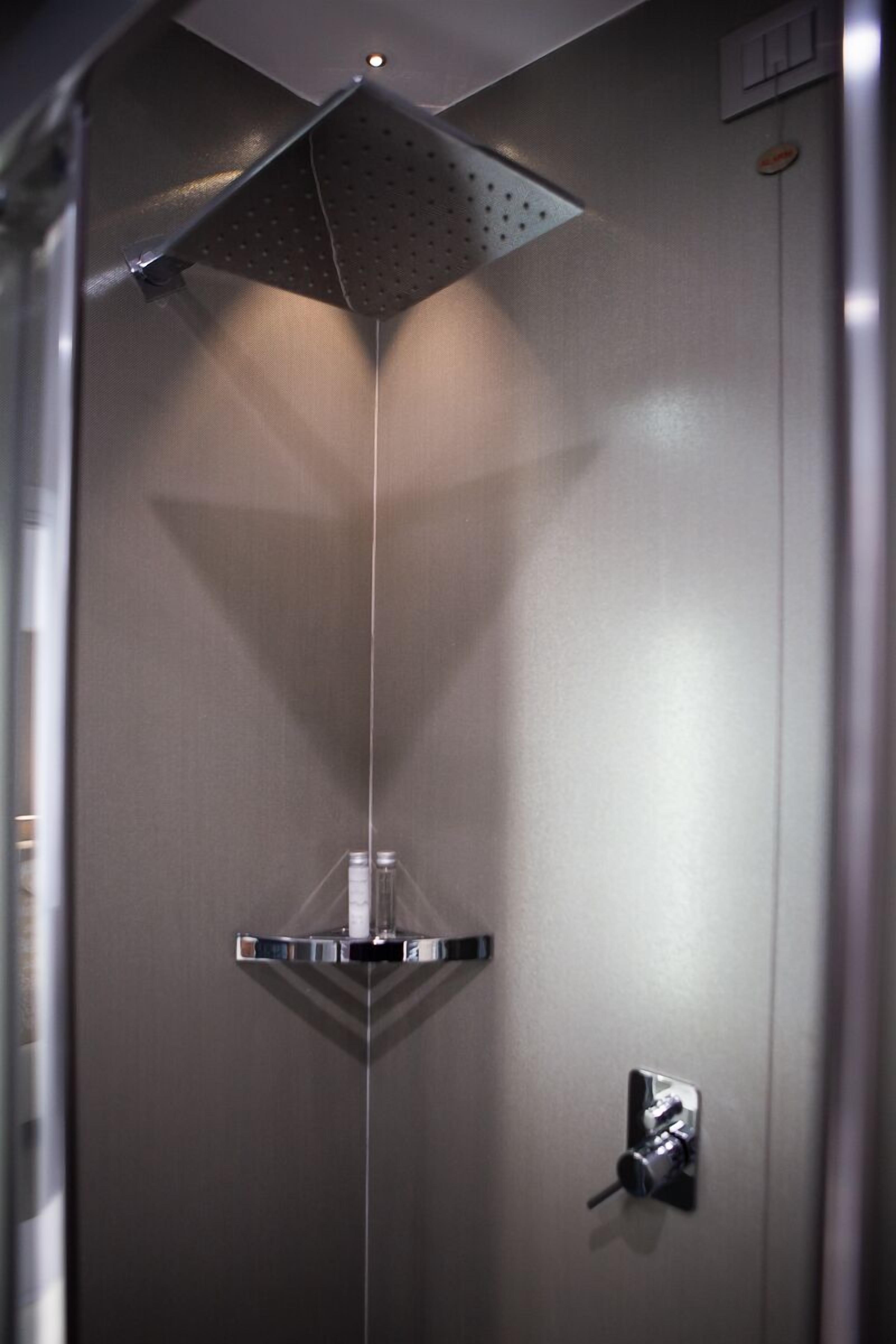 En moderne elevator med gelænder i metal og et kontrolpanel på væggen.