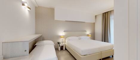 Una habitación de hotel moderna con dos camas individuales, una mesita de noche con lámpara, un estante empotrado y un ventanal con cortinas.