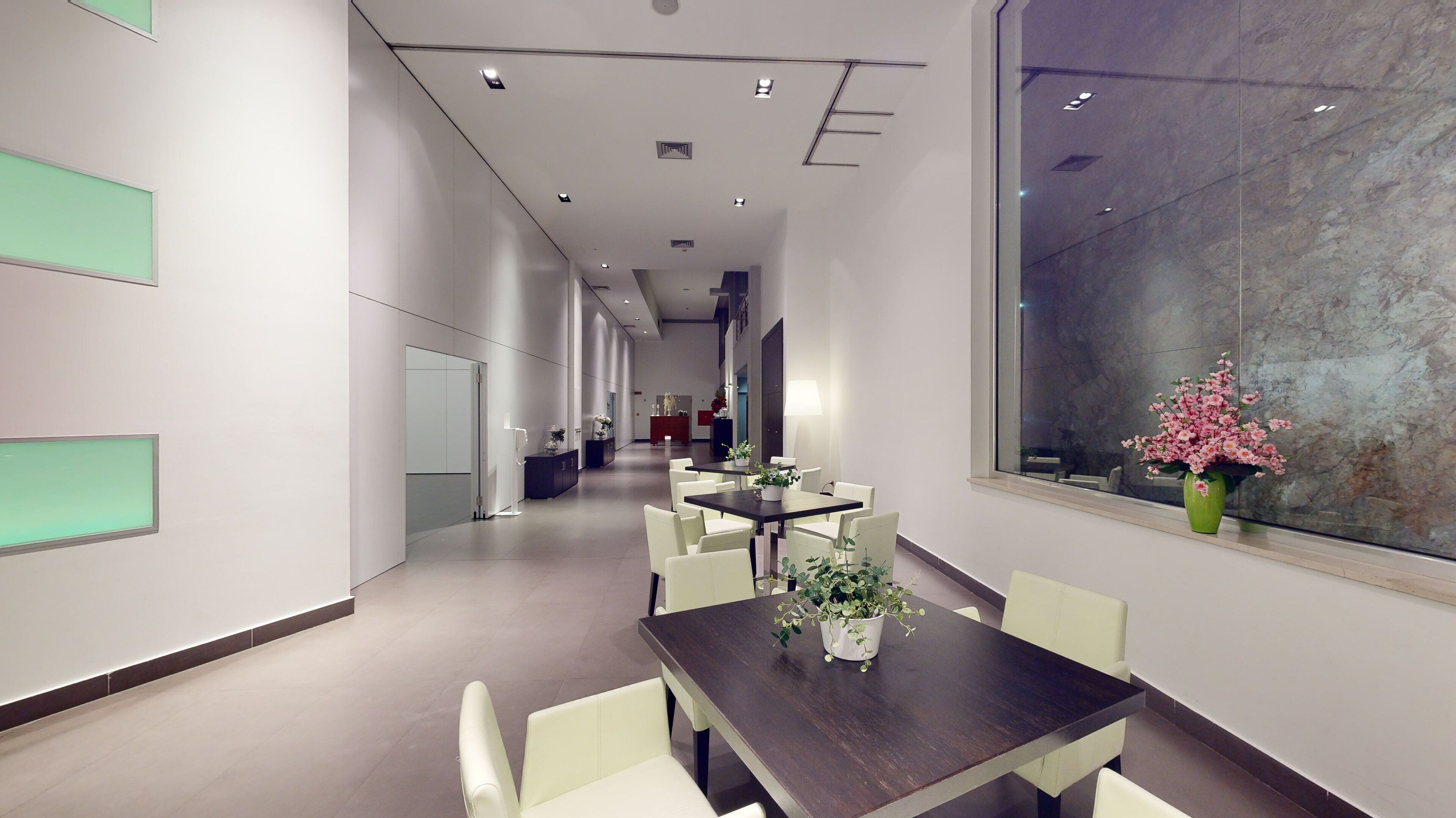 A modern conference room with a long table and chairs, a large window with a view, and a reception area in the background.