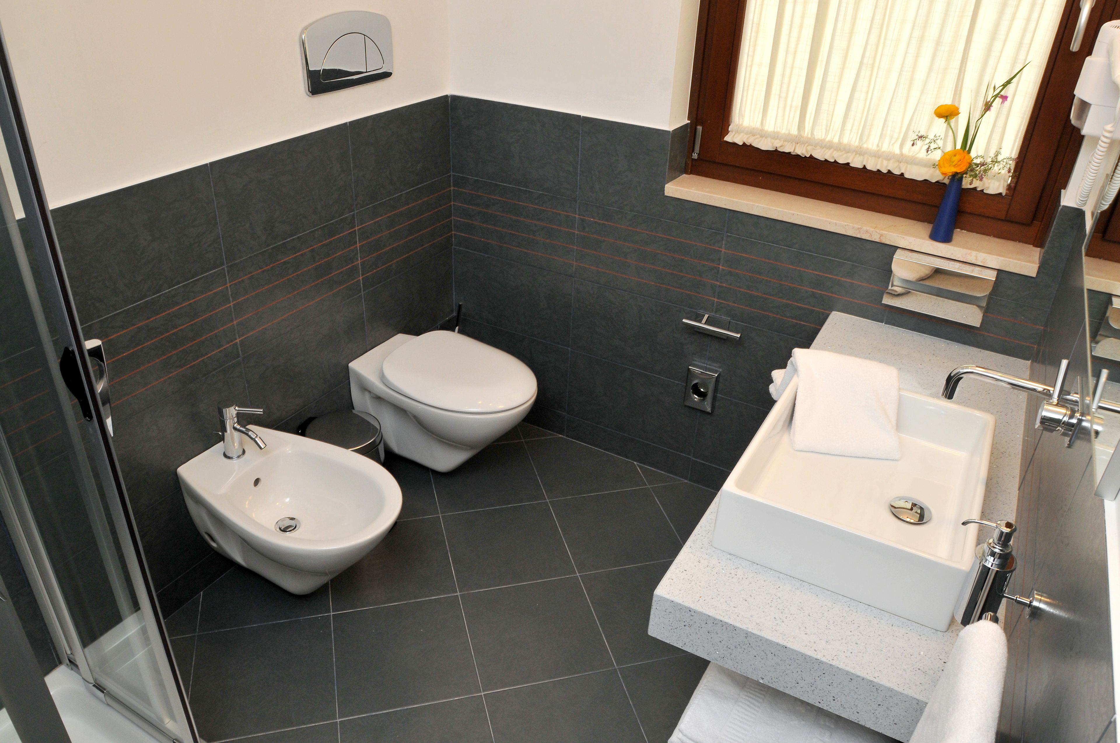 A modern bathroom with a bidet, toilet, and sink.