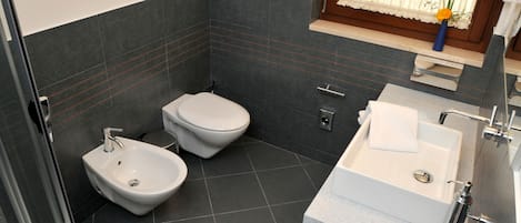 A modern bathroom with a bidet, toilet, and sink.