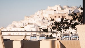 A table set with glasses and a plant, overlooking a cityscape. - Hotel Monte Sarago (Ostuni)