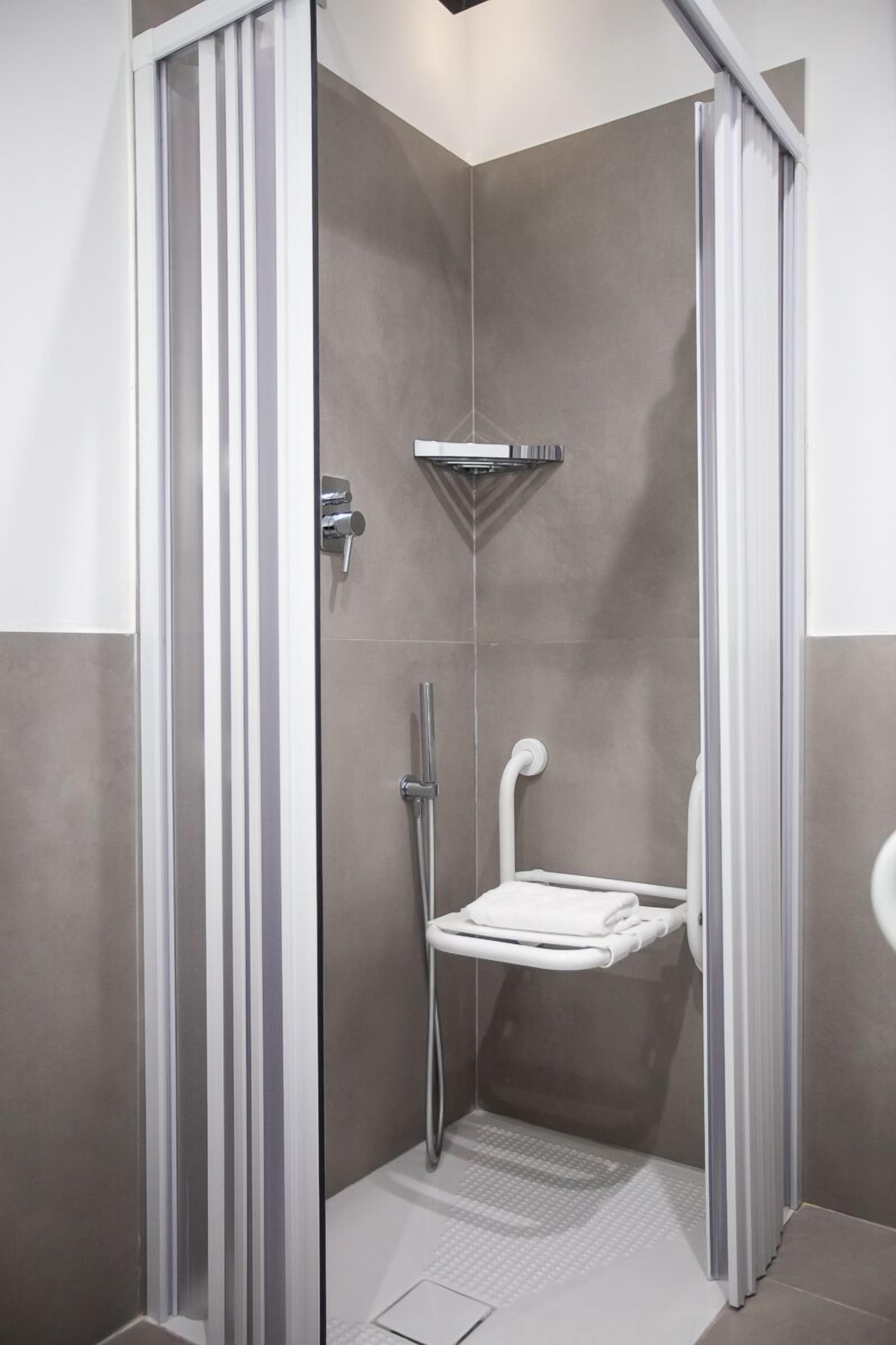 Une cabine de douche moderne dotée d’une porte en verre, d’un porte-serviettes et d’un pommeau de douche à main.