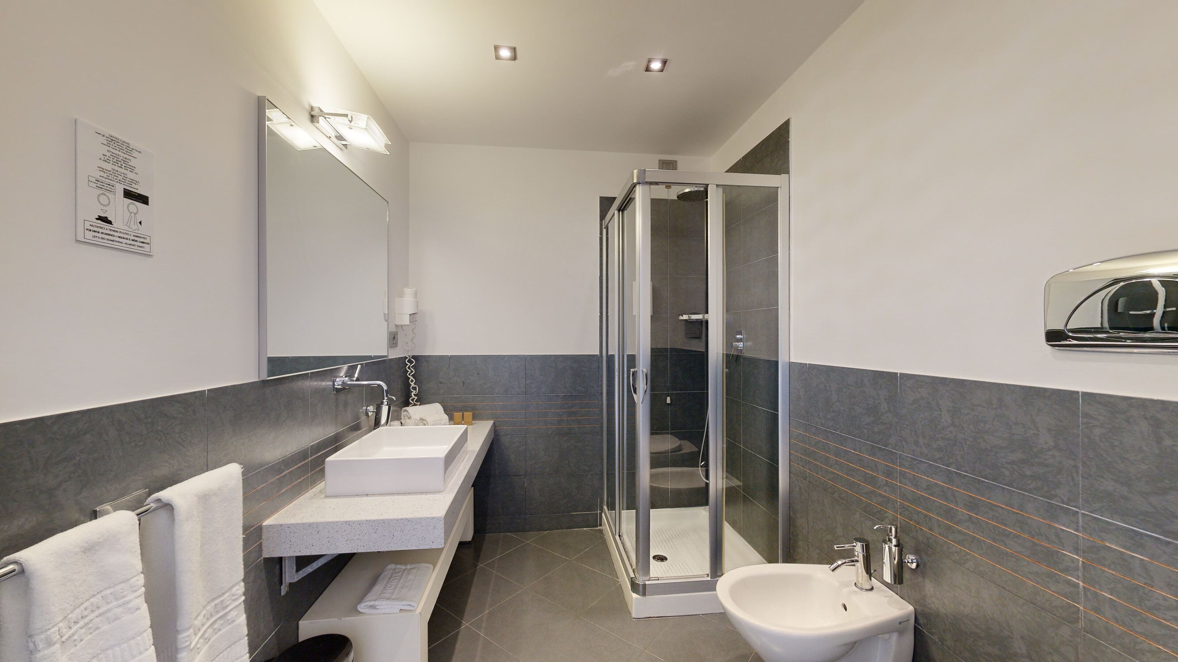 Une salle de bain moderne avec une douche à parois de verre, un lavabo et un miroir.