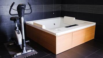 Une salle de bain moderne équipée d’un vélo d’exercice intégré, d’une grande baignoire et de meubles en bois.